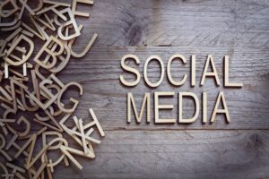 Holzbuchstaben, die auf einer hölzernen Oberfläche verstreut sind, mit den Worten SOCIAL MEDIA, die auf der rechten Seite des Bildes fein säuberlich geschrieben sind.